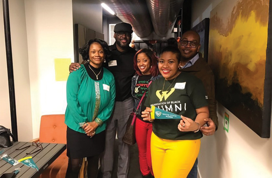 Members of the Organization of Black Alumni smiling, posing for a picture inside the hallway of a WSU building