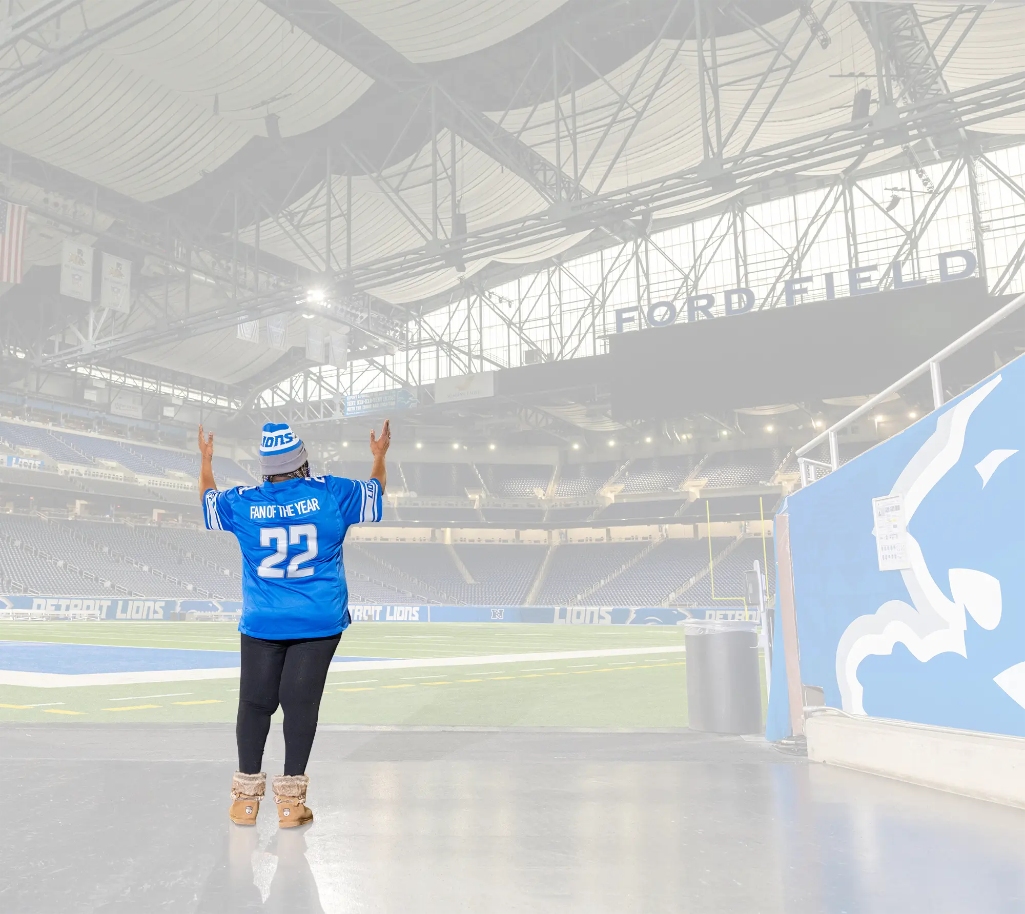 Denise Ford in her #22 Fan of the Year Lions jersey standing at the stadium team tunnel exit looking out at Ford Field