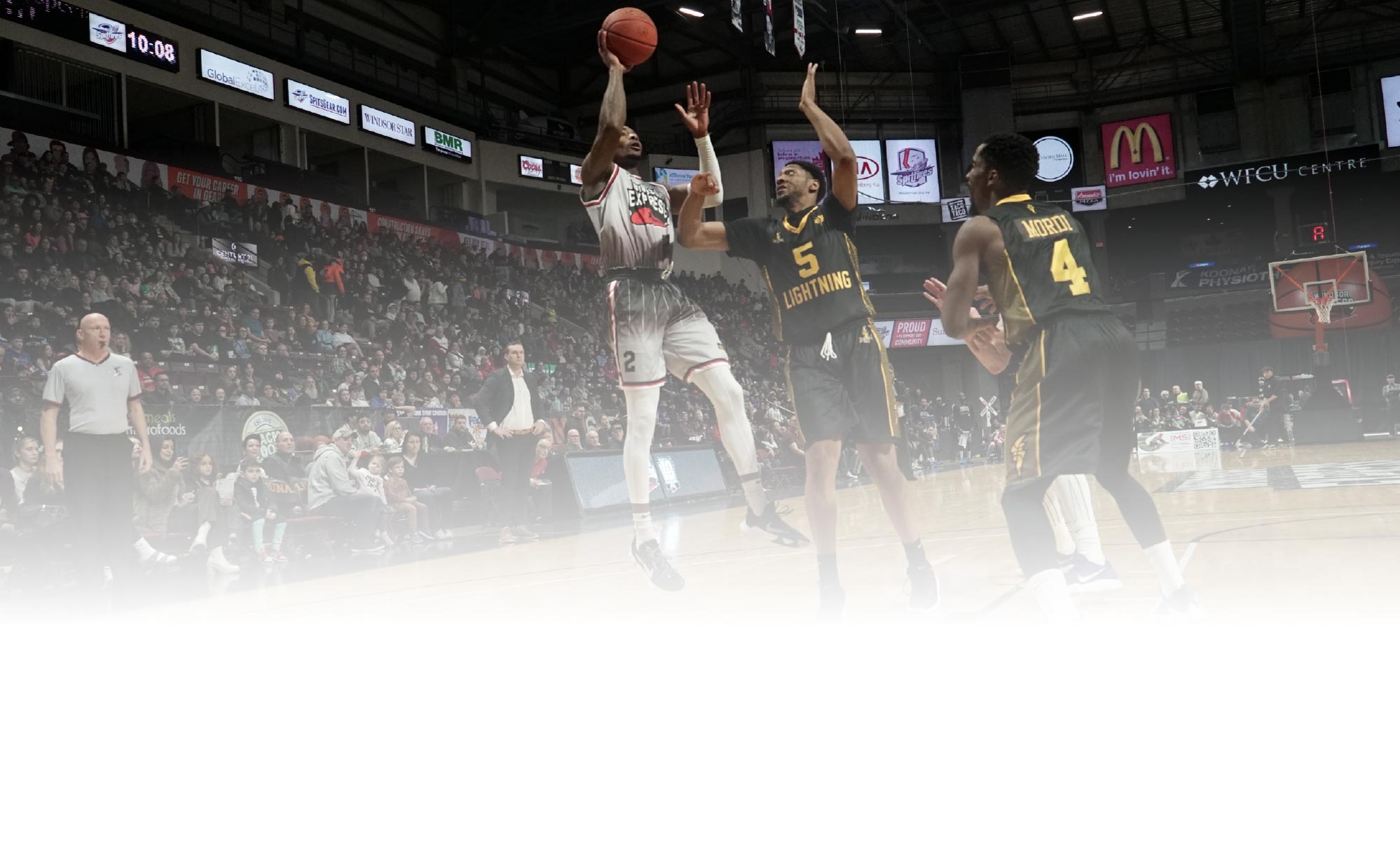 court view of a player jumping for a shot against two opposing players during a basketball game